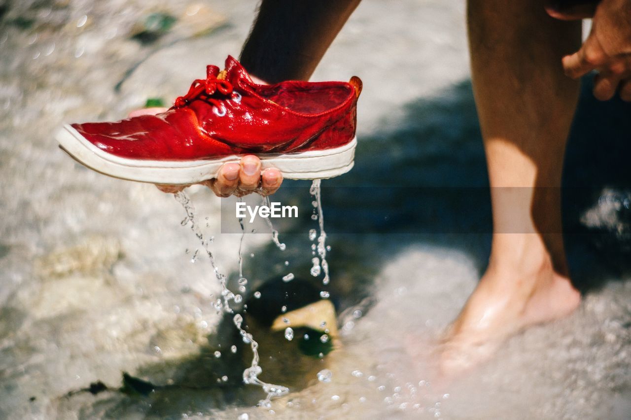 Low section of man holding wet shoe in river