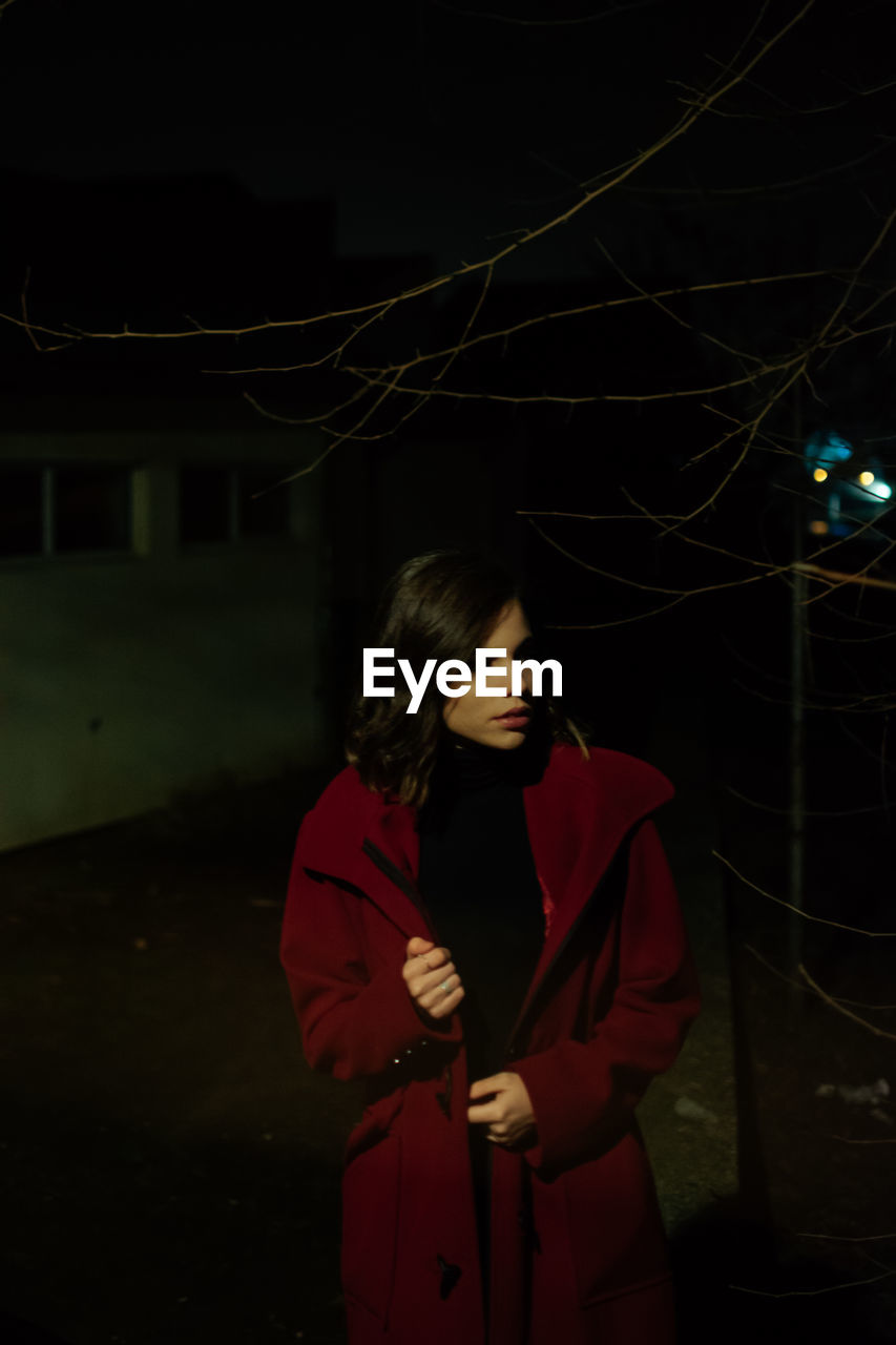 A young woman wearing warm clothing outdoors at night during winter