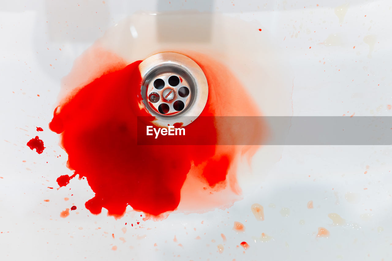 Splashes of blood and water flow into a white sink. pool of blood close-up, accident in the bathroom