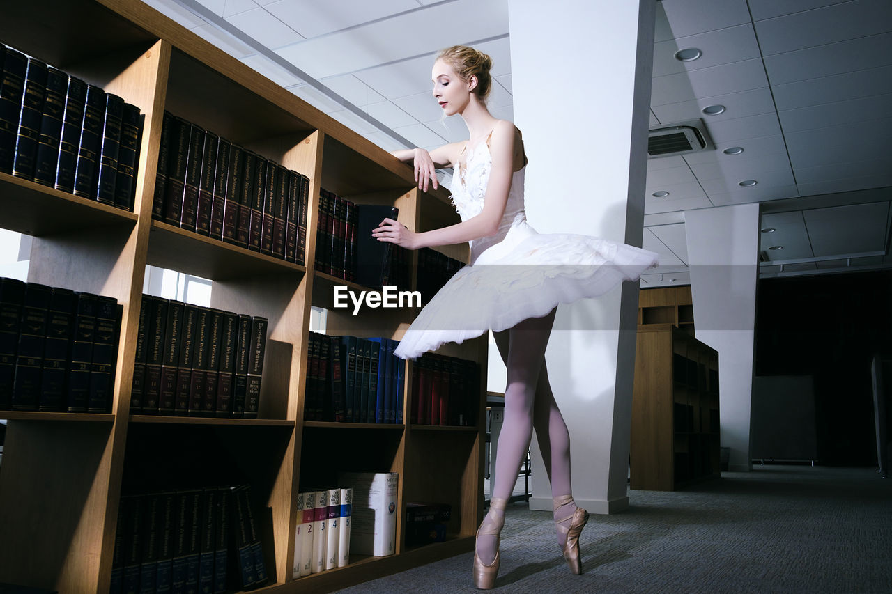 A charming ballerina went to the library to choose a new book during a break