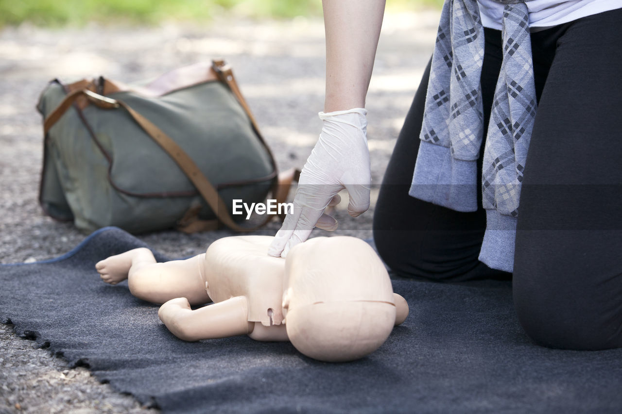 Midsection of paramedics performing cpr on baby mannequin