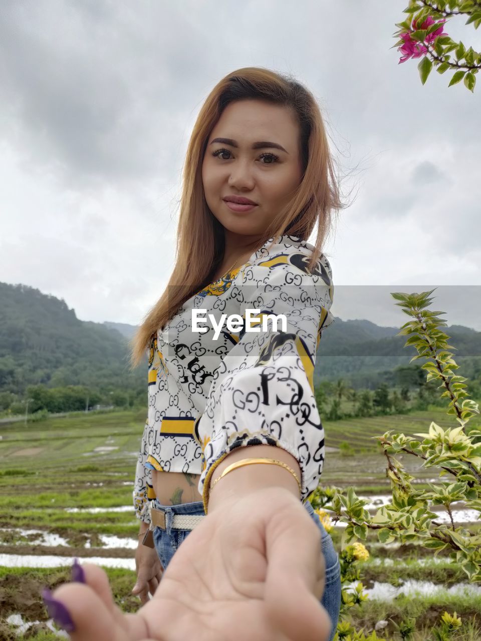 PORTRAIT OF SMILING YOUNG WOMAN AGAINST SKY ON FIELD