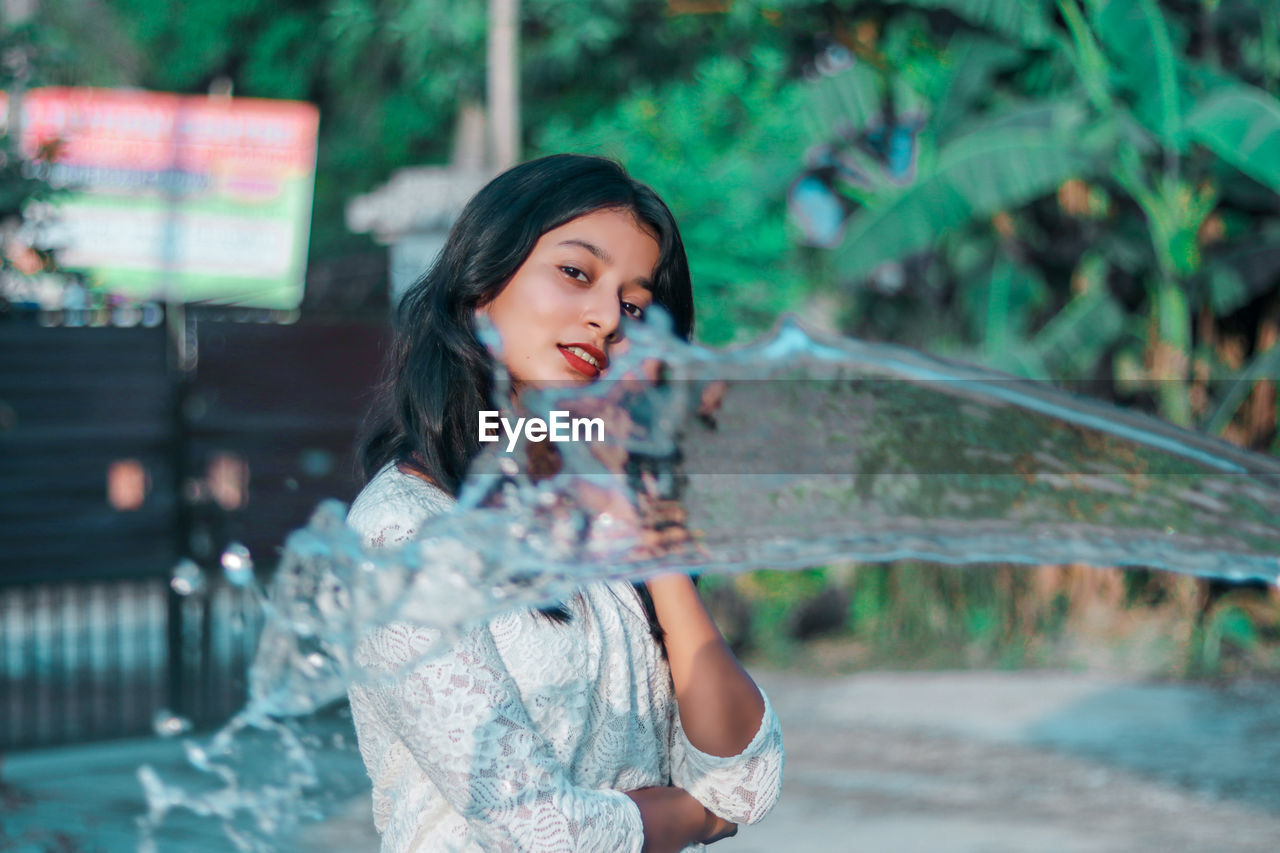 Water splashing against smiling young woman in background