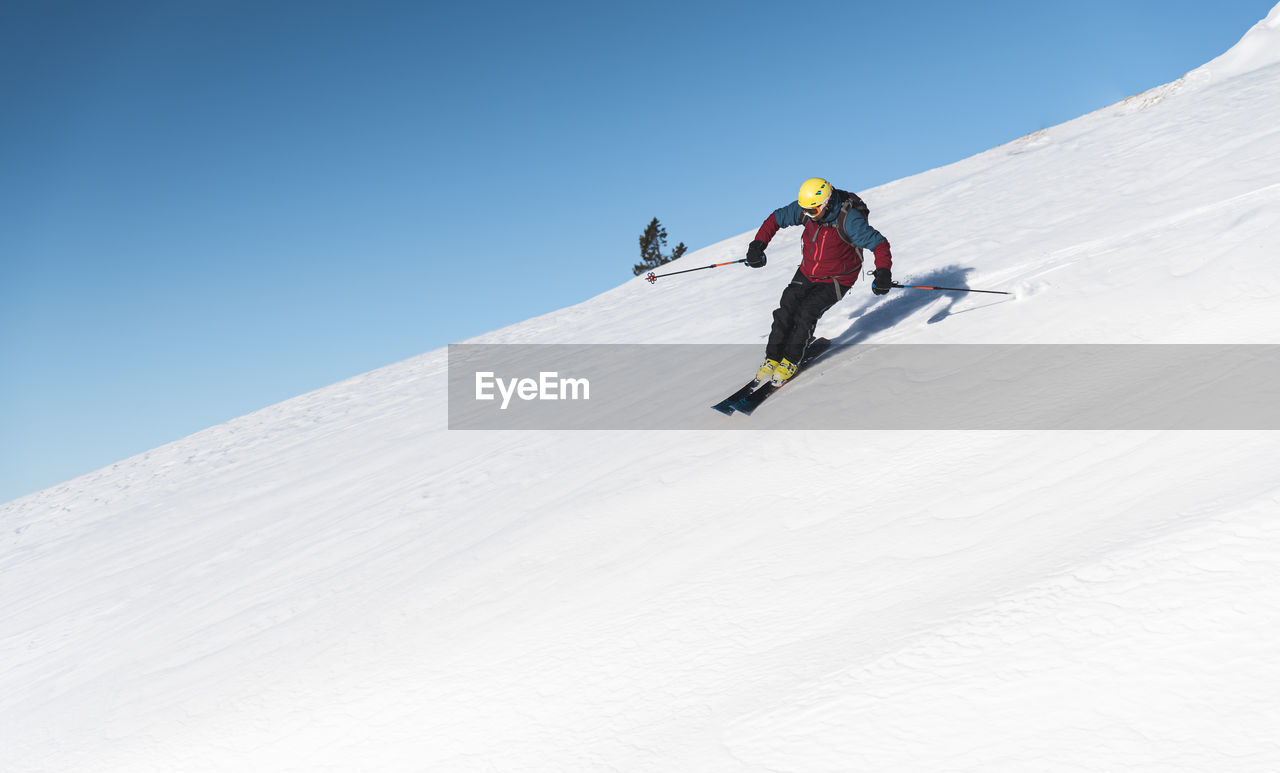Mature man skiing on mountain slope against sky