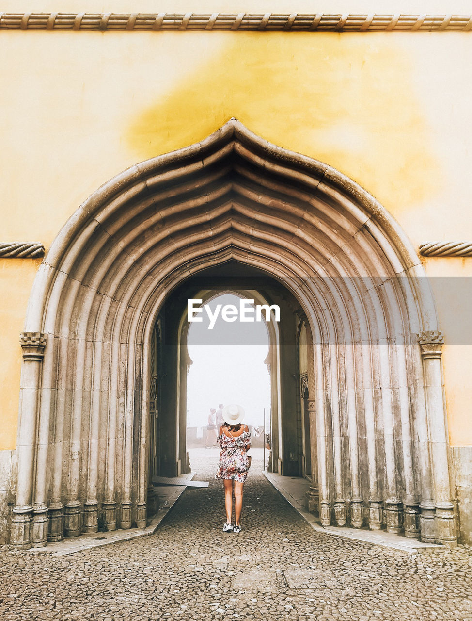 Rear view of woman walking against arch