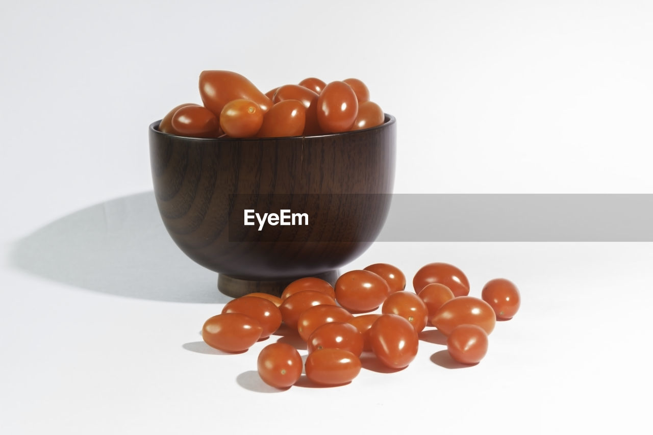 High angle view of cherry tomatoes in bowl against white background