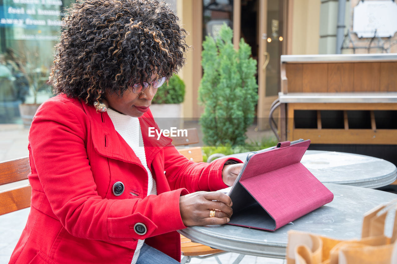 A young african american woman in a red coat cheking bill after shopping