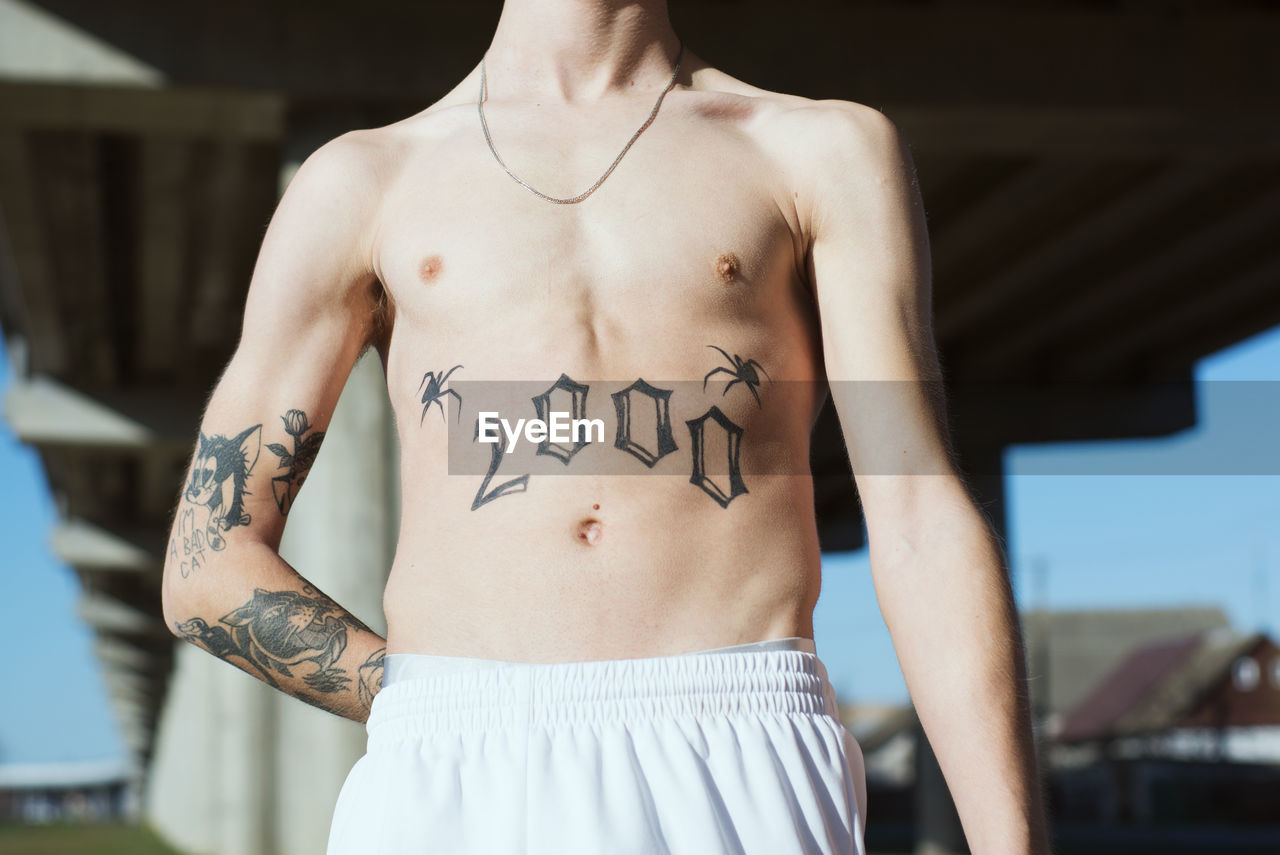 Midsection of man shirtless man with tattoo