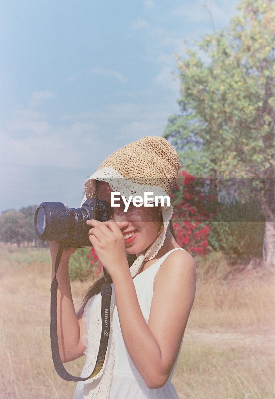 Portrait of woman holding camera on field