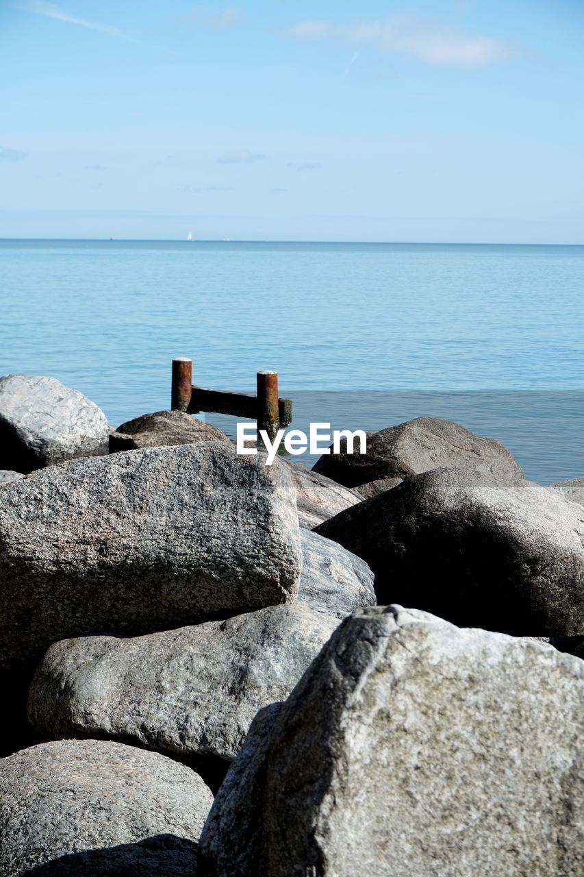 Rocks on shore by sea against sky