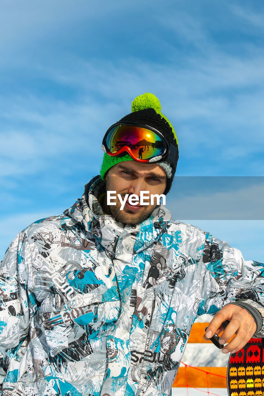 adult, one person, sky, portrait, men, leisure activity, nature, fashion, looking at camera, young adult, sports, day, clothing, cloud, front view, sunglasses, extreme sports, waist up, ski goggles, glasses, blue, emotion, outdoors, snow, cold temperature, winter, lifestyles, standing, smiling, vacation, mountain, holiday, happiness, fun, trip