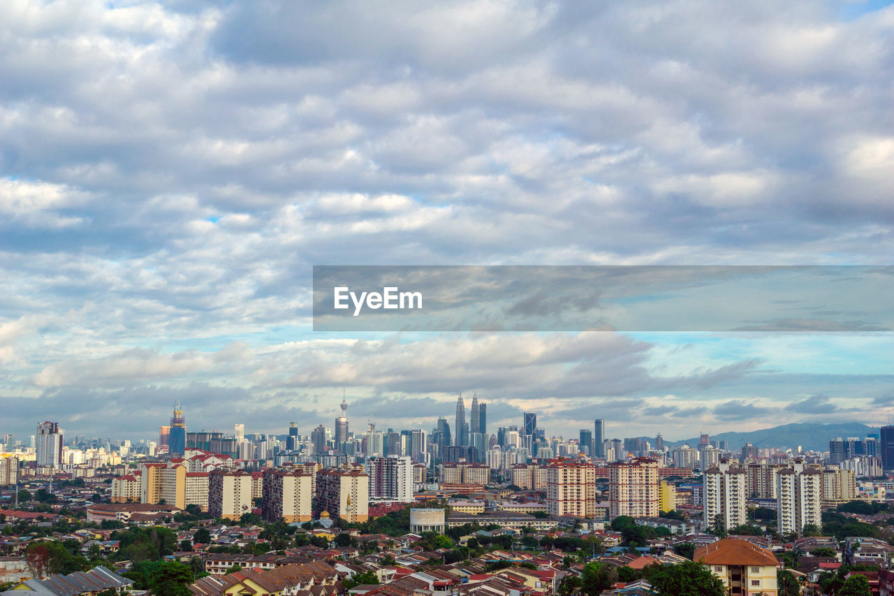 View of cityscape against cloudy sky