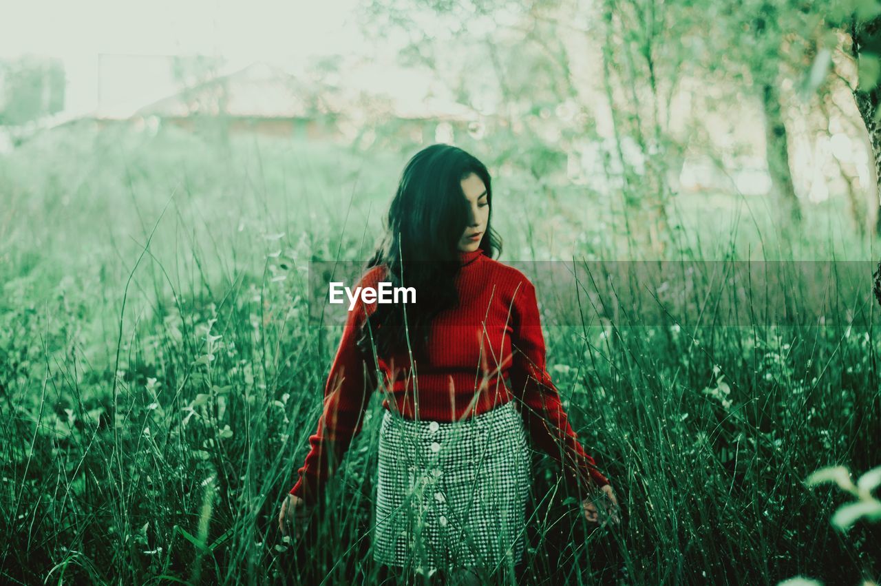 FULL LENGTH OF YOUNG WOMAN STANDING ON GRASS