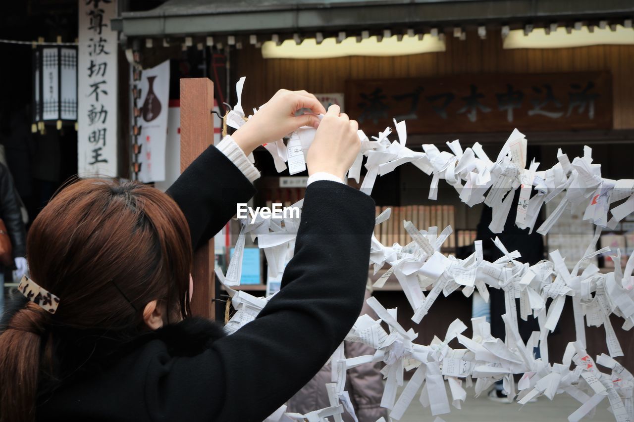 Rear view of woman tying paper at temple