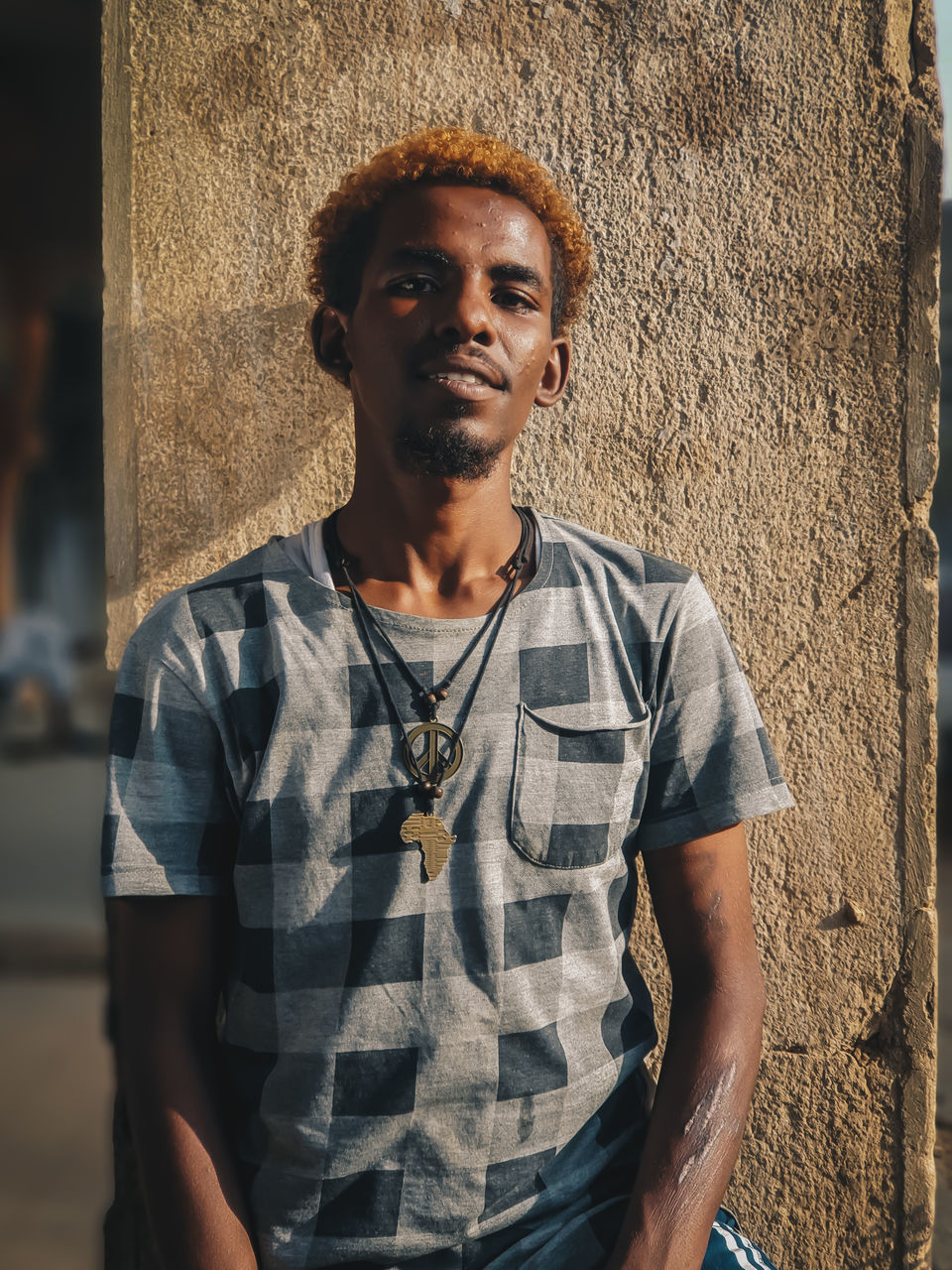 Portrait of young man standing against wall