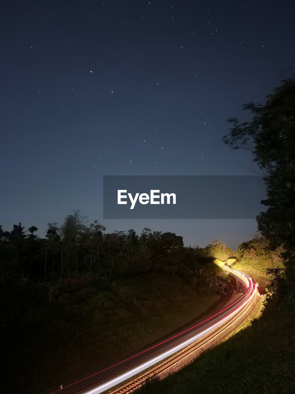 Light trails on road against sky at night