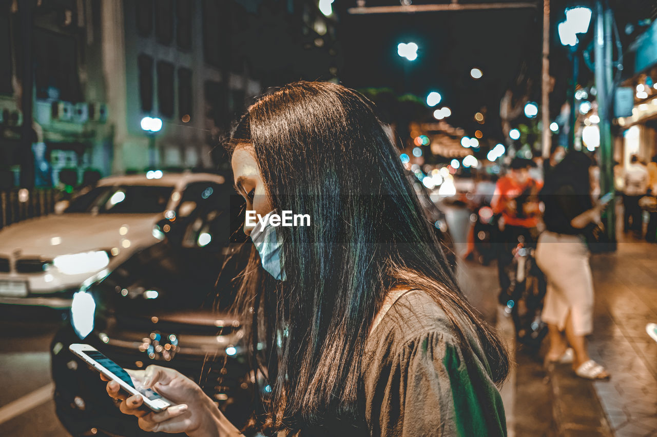 Portrait of woman in illuminated city at night