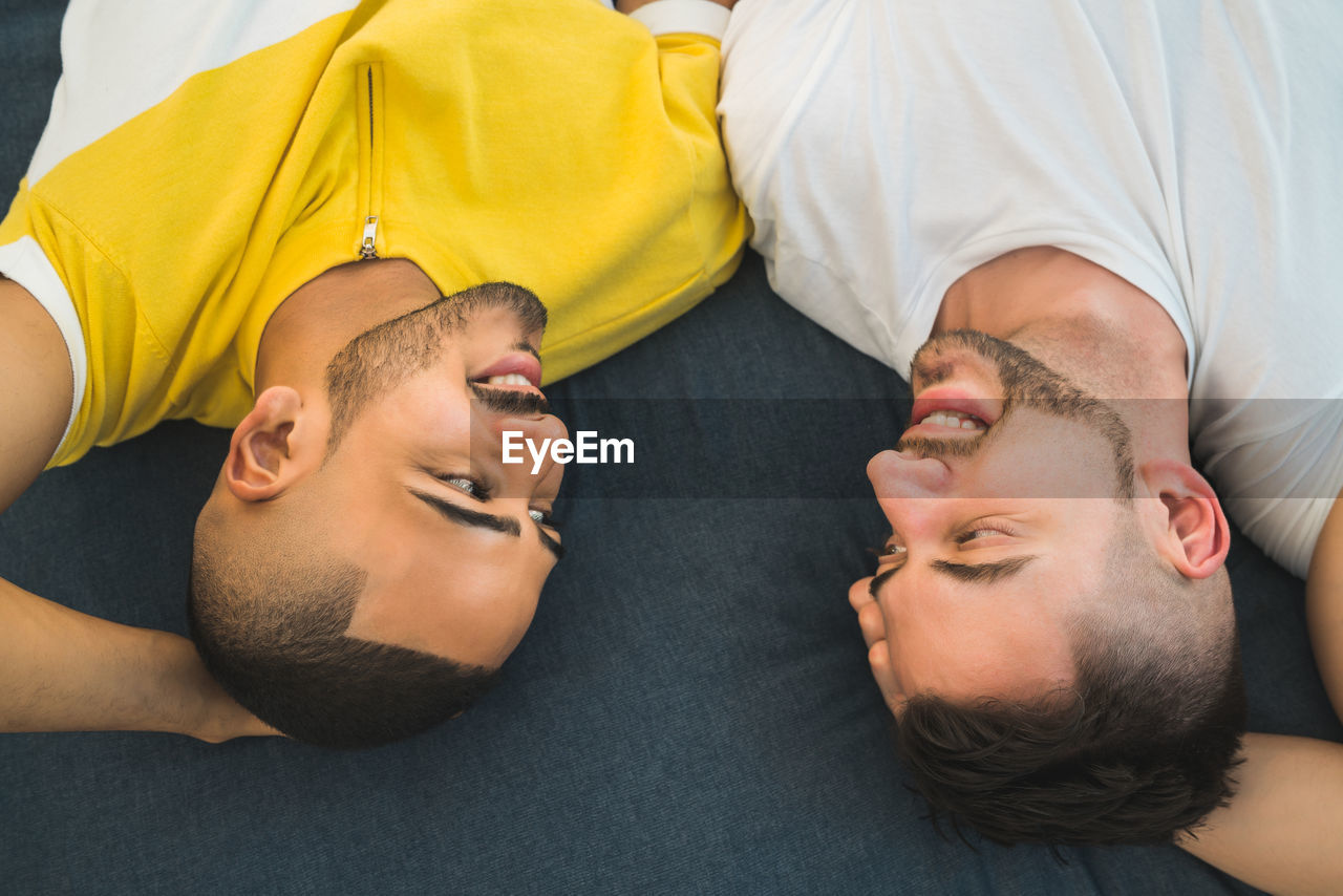 High angle view of gay couple relaxing on bed at home