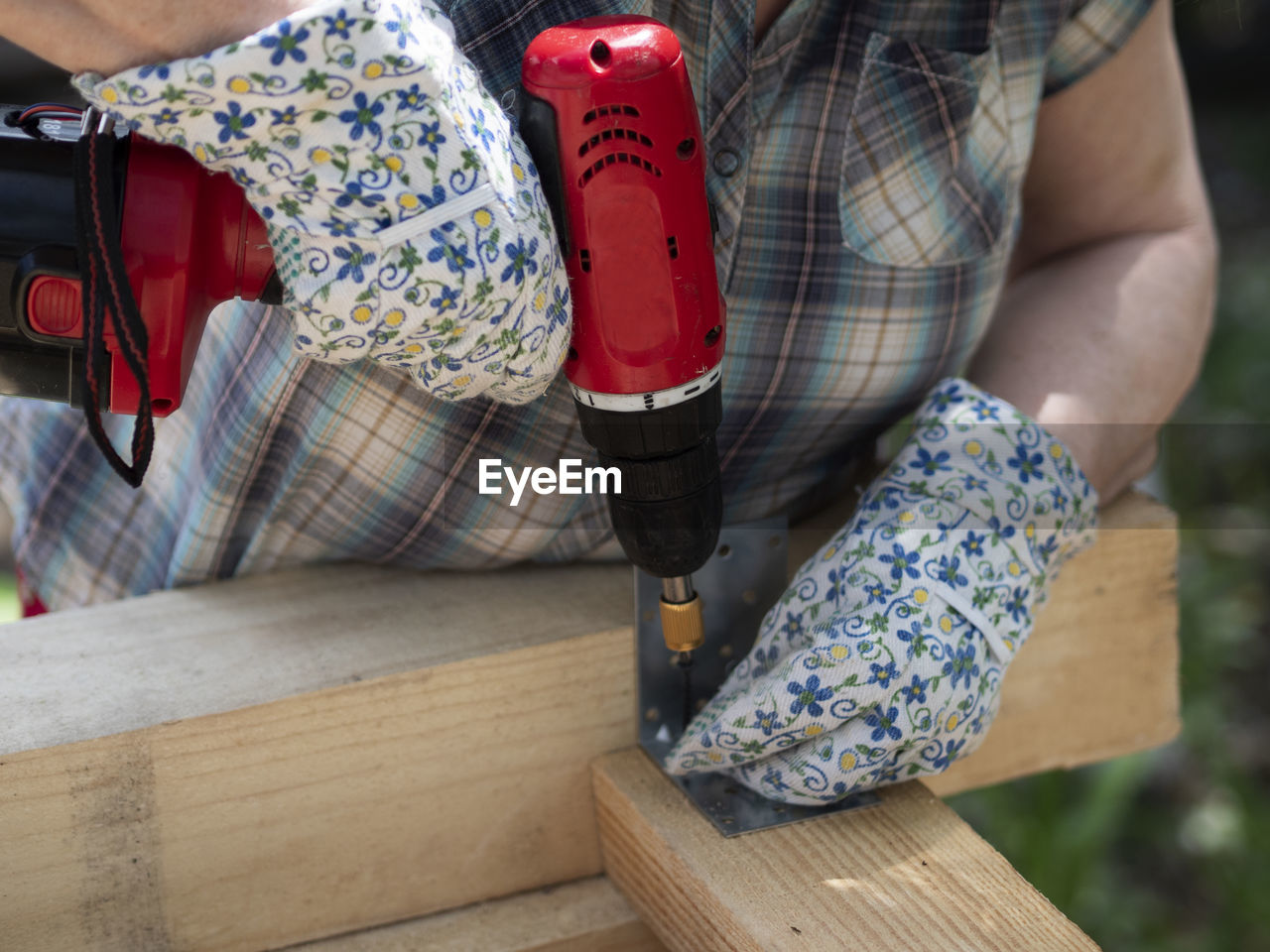 Hands of senior caucasian woman assembles frame of building using metal fasteners using screwdriver