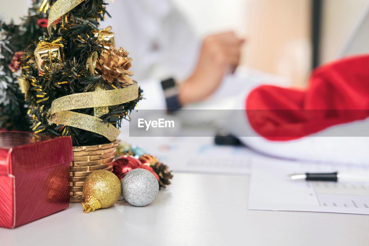 Midsection of business colleagues discussing over graph with christmas decorations on table