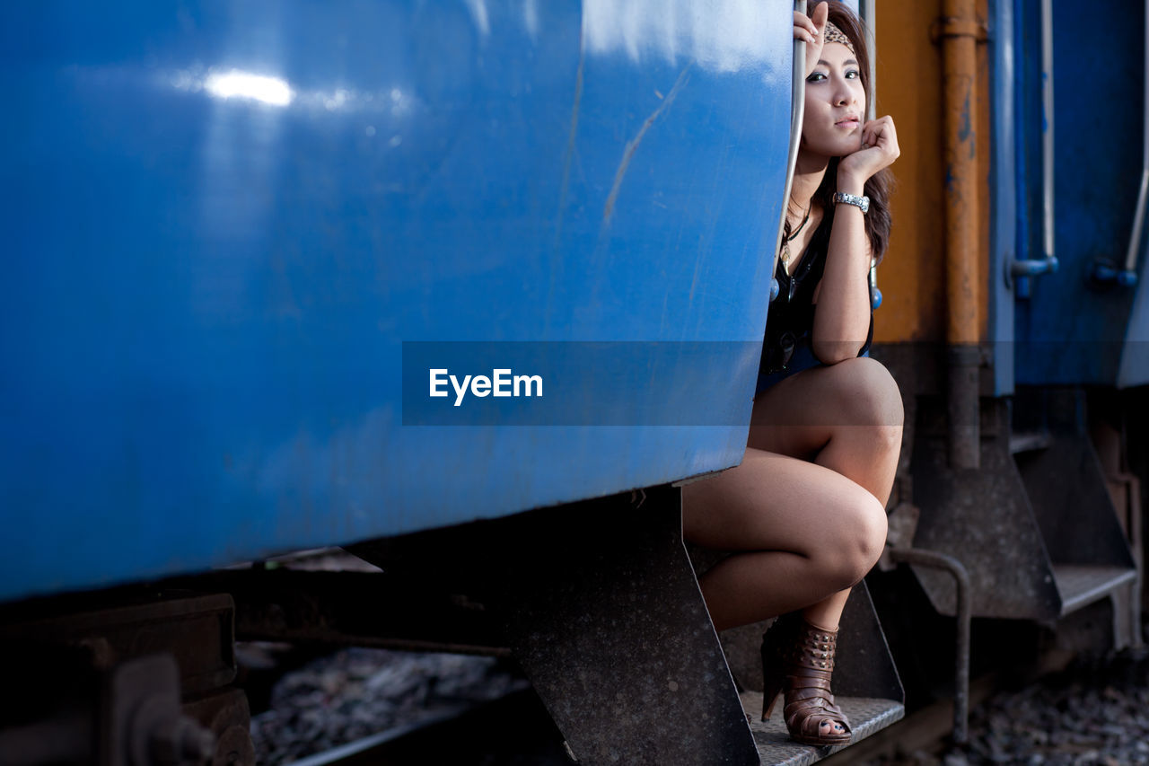 Fashionable woman sitting on train door