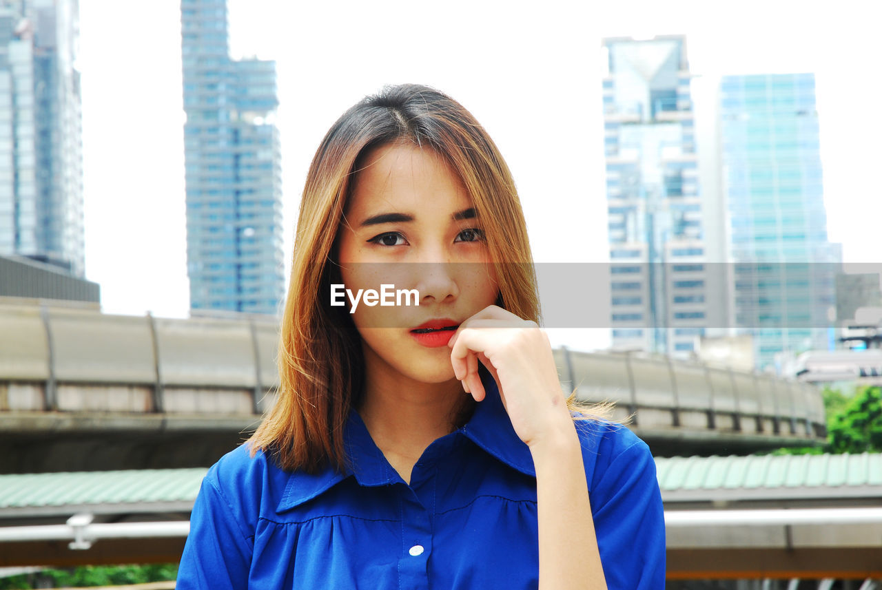 Close-up portrait of young woman standing in city