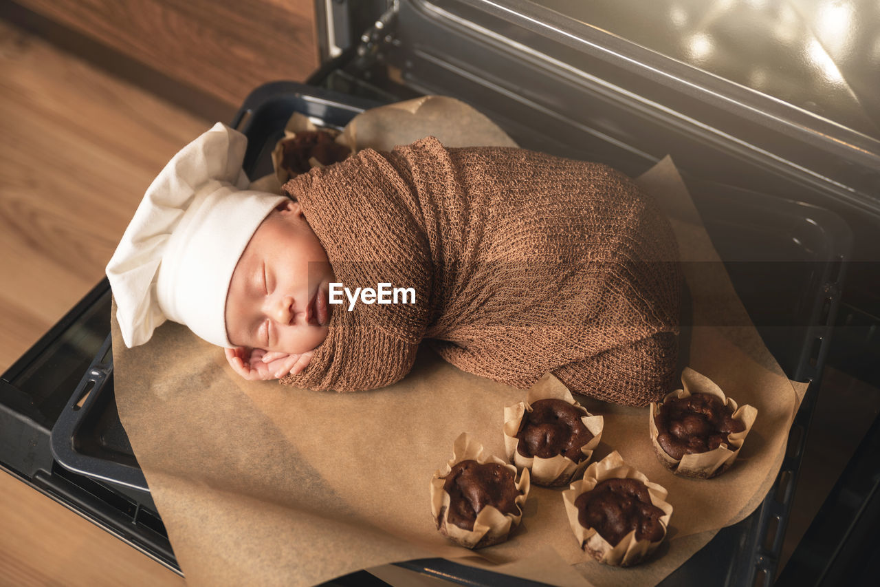 High angle view cute baby sleeping by microwave