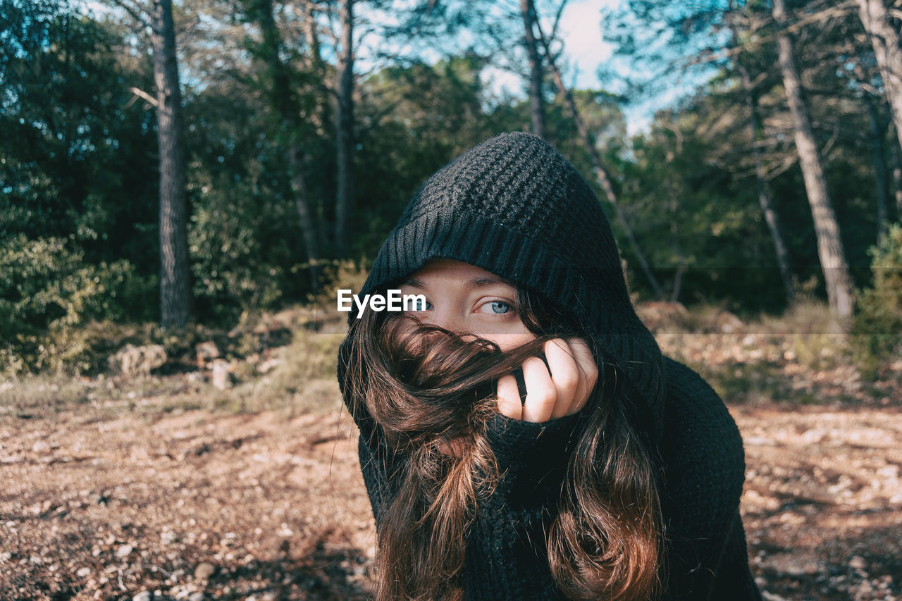 Portrait of young woman covering face with hair in forest