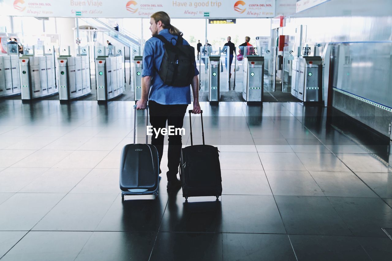 FULL LENGTH OF MAN TRAVELING IN AIRPORT AT SUBWAY