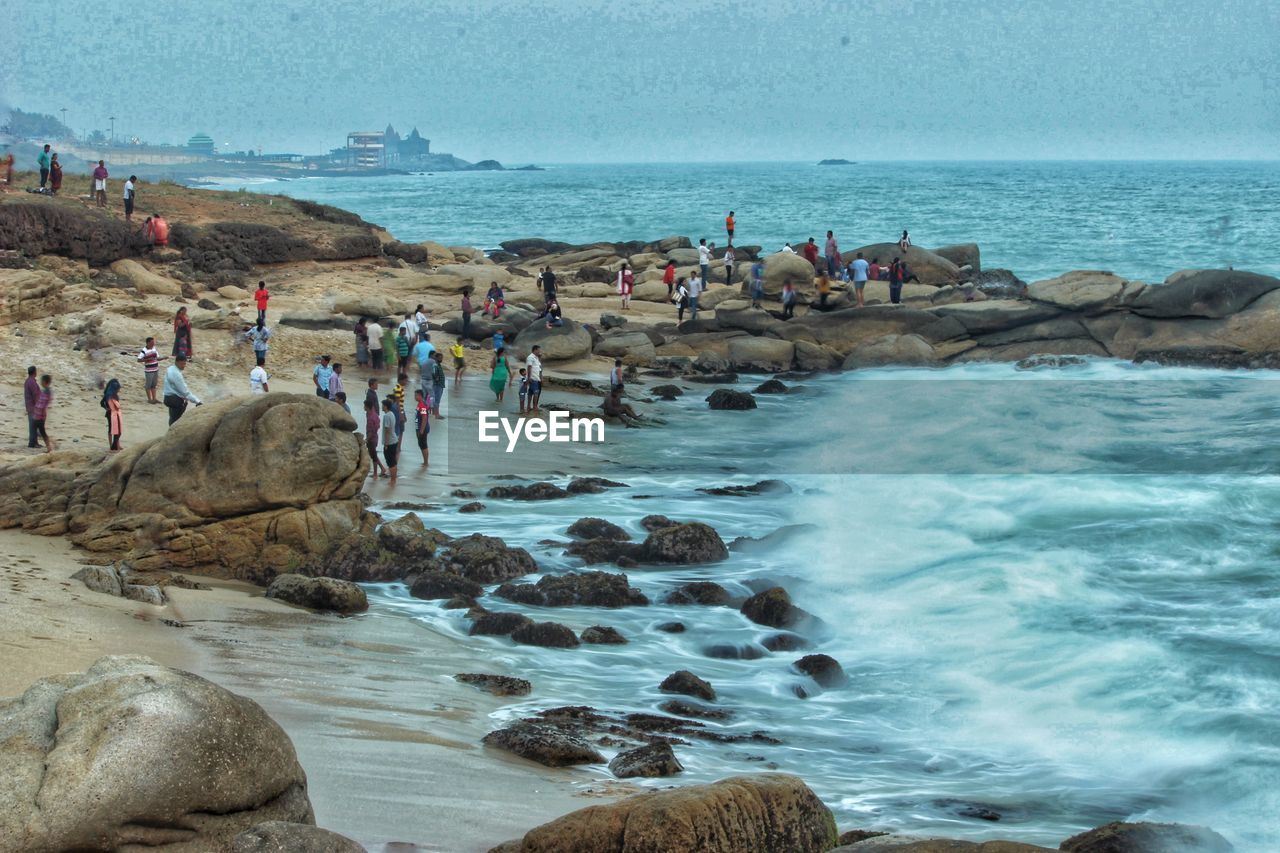 PEOPLE AT BEACH AGAINST SKY