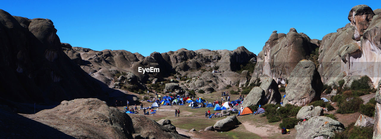 People camping amidst rock formations against clear sky