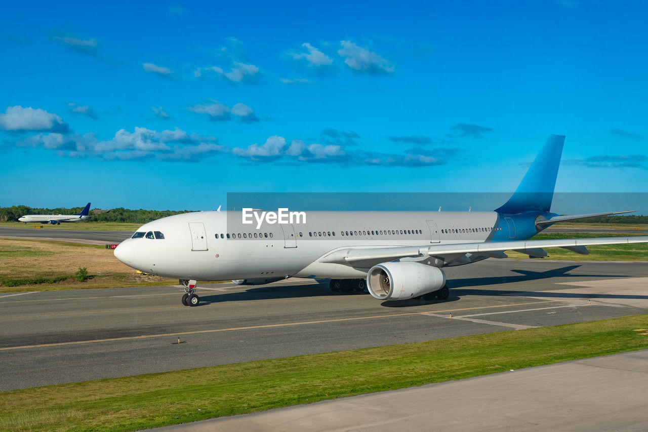 transportation, air vehicle, airplane, mode of transportation, airliner, airport, travel, air travel, airport runway, wide-body aircraft, vehicle, sky, aircraft, business, aerospace industry, jet aircraft, nature, aircraft wing, aviation, blue, flying, business travel, road, journey, engine, airfield, takeoff, environment, cloud, technology, no people, arriving, jet engine, narrow-body aircraft, business finance and industry, asphalt, outdoors, private airplane, taking off, landing, land