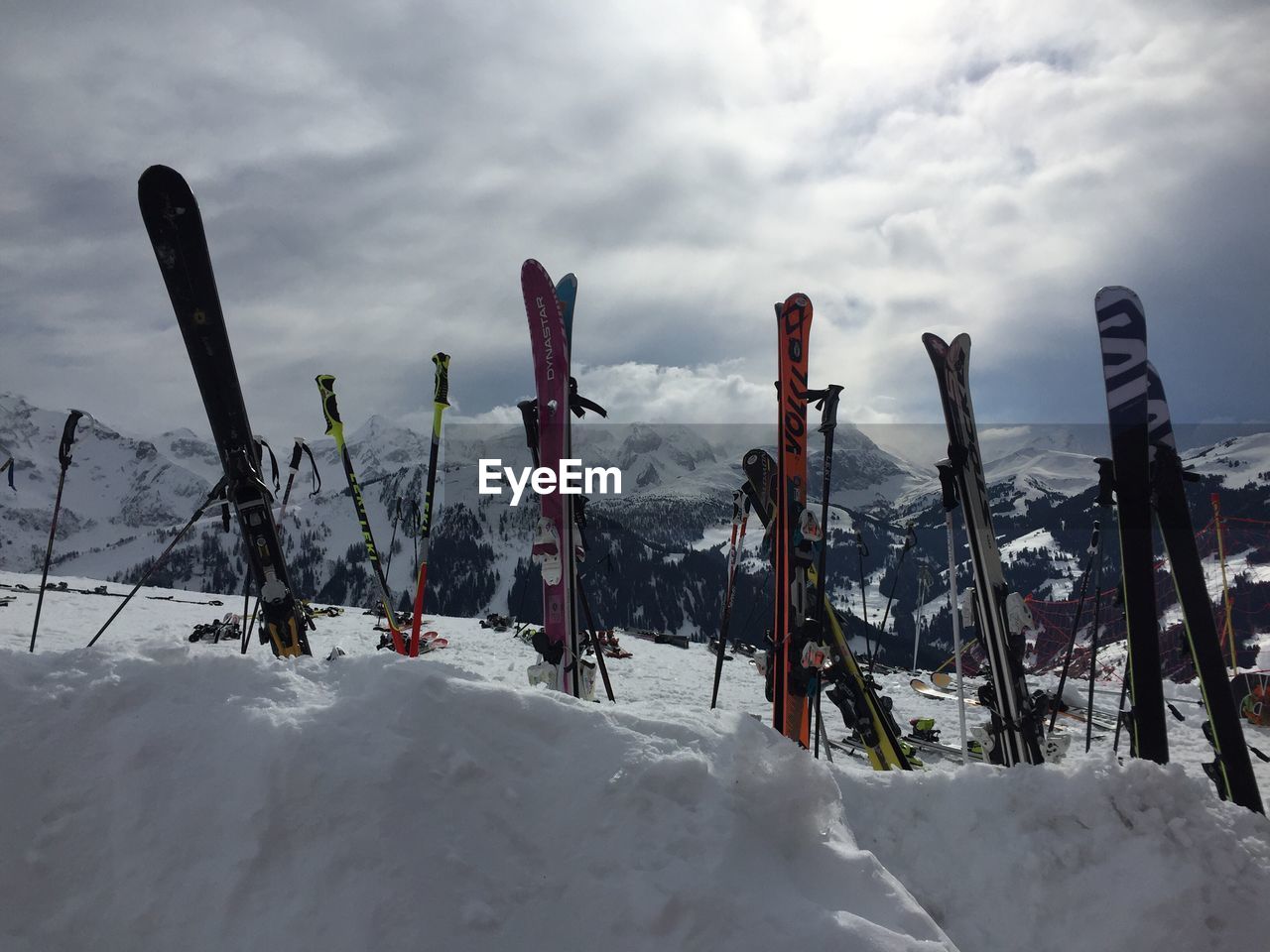 Ski poles on snowcapped mountain against cloudy sky