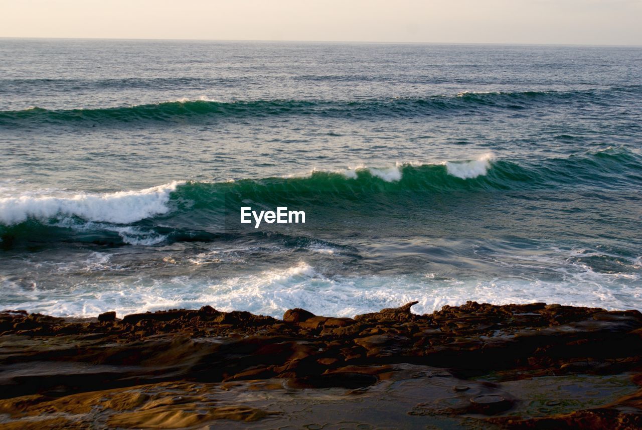 Waves flowing at sea against sky