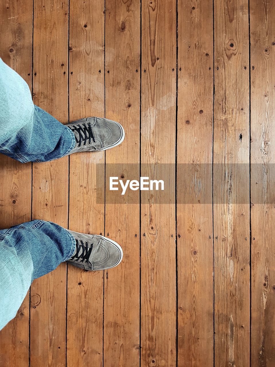 Low section of man wearing shoes standing on floorboard