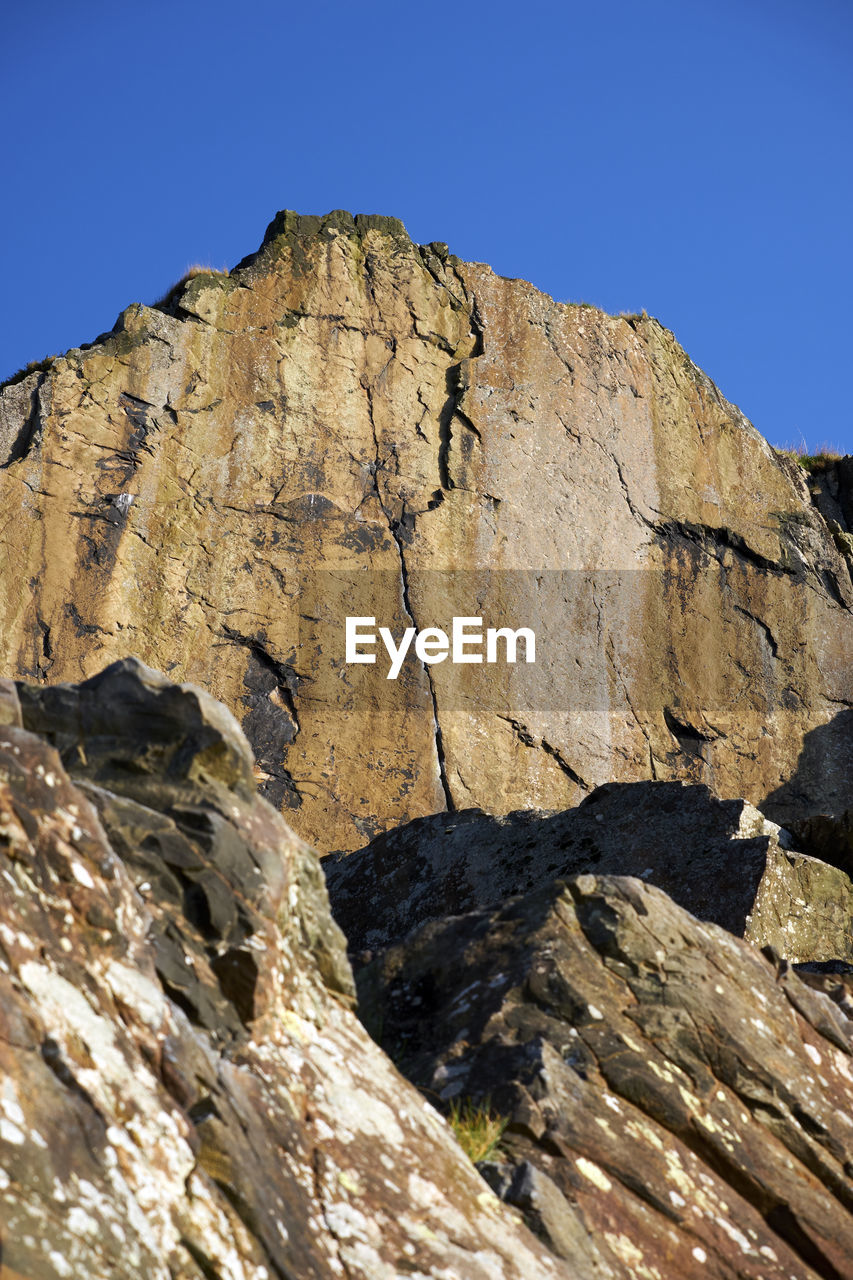 LOW ANGLE VIEW OF ROCKS AGAINST BLUE SKY