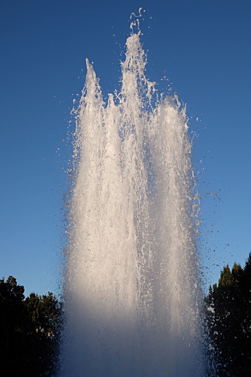 Low angle view of water splashing in fountain against sky