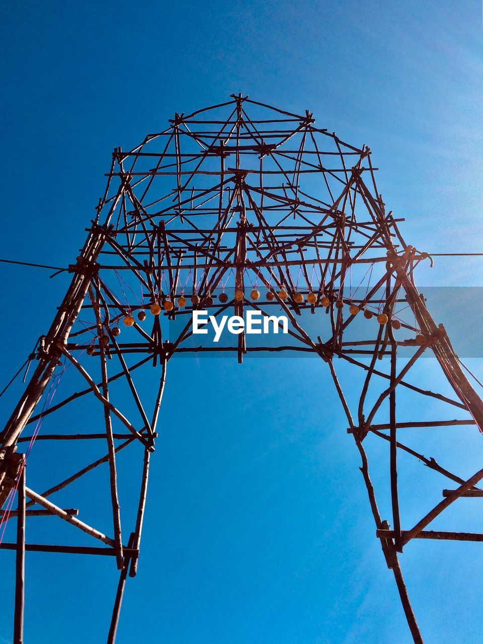 Low angle view of electricity pylon against blue sky