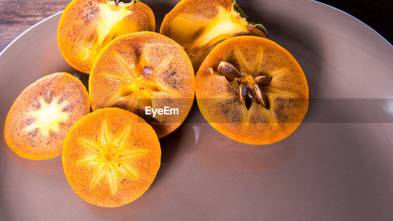 Persimmon on a plate on a wooden table,copy space