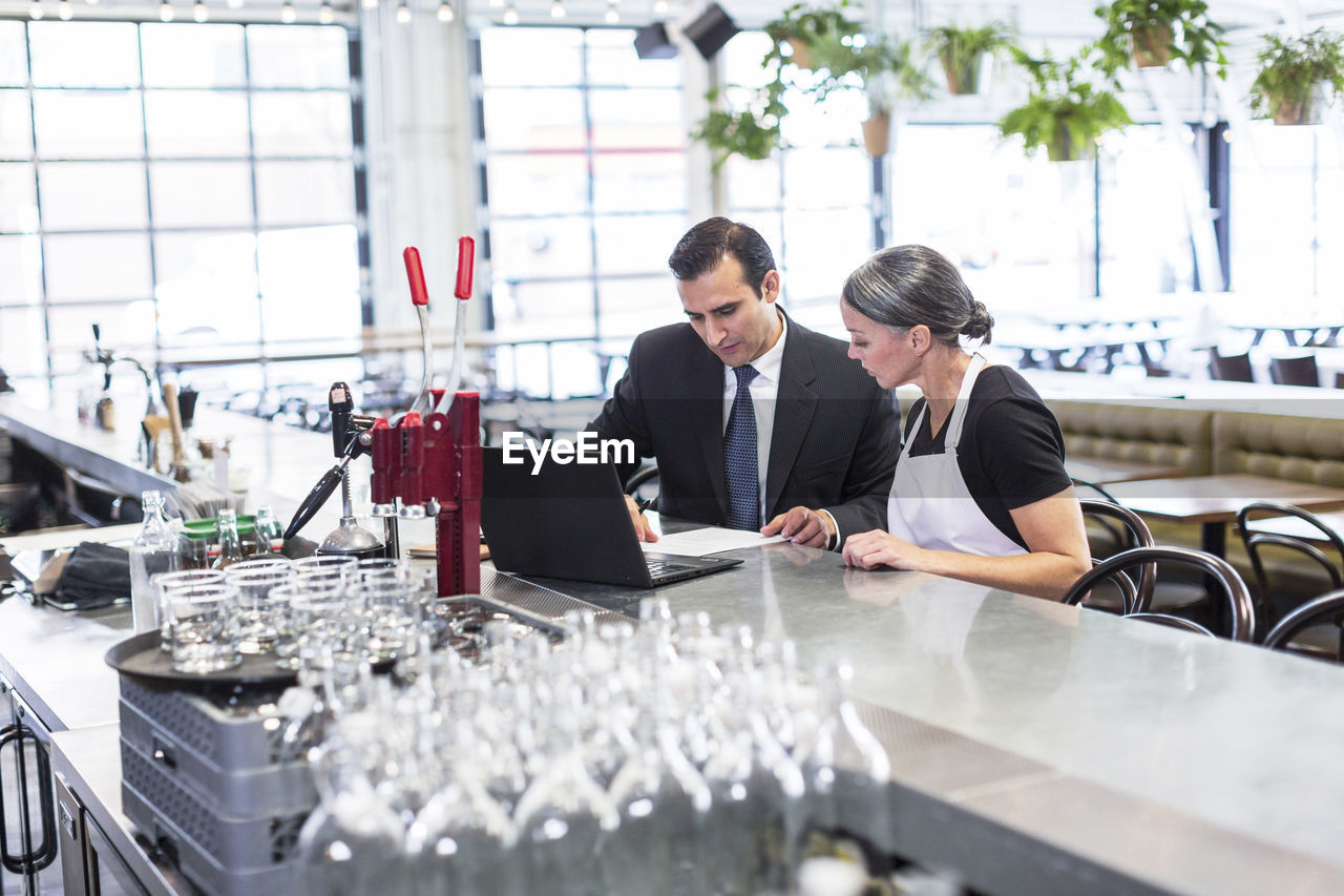 High angle view of businessman discussing with female chef at table in restaurant