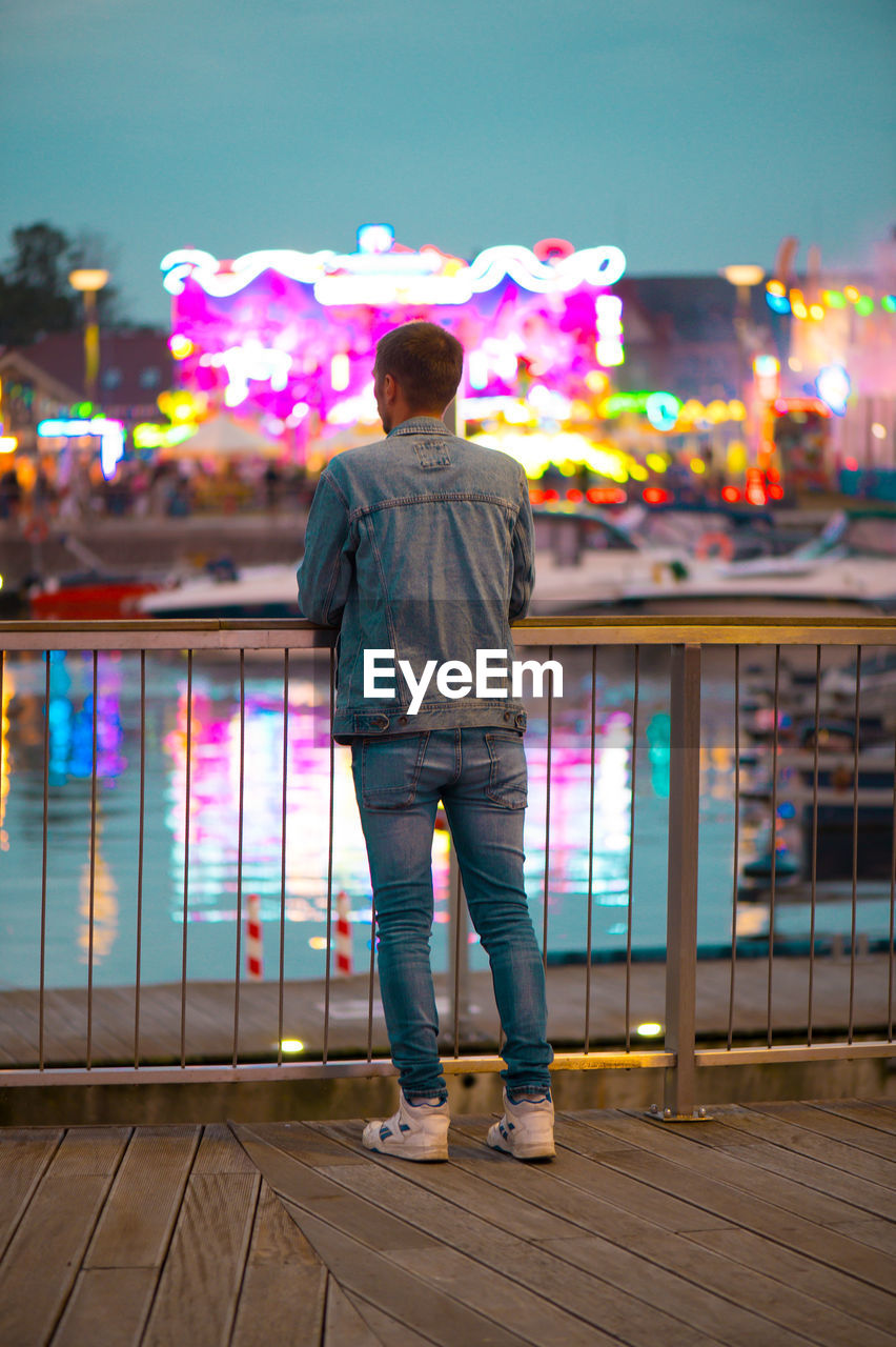 Rear view of man walking on street at night