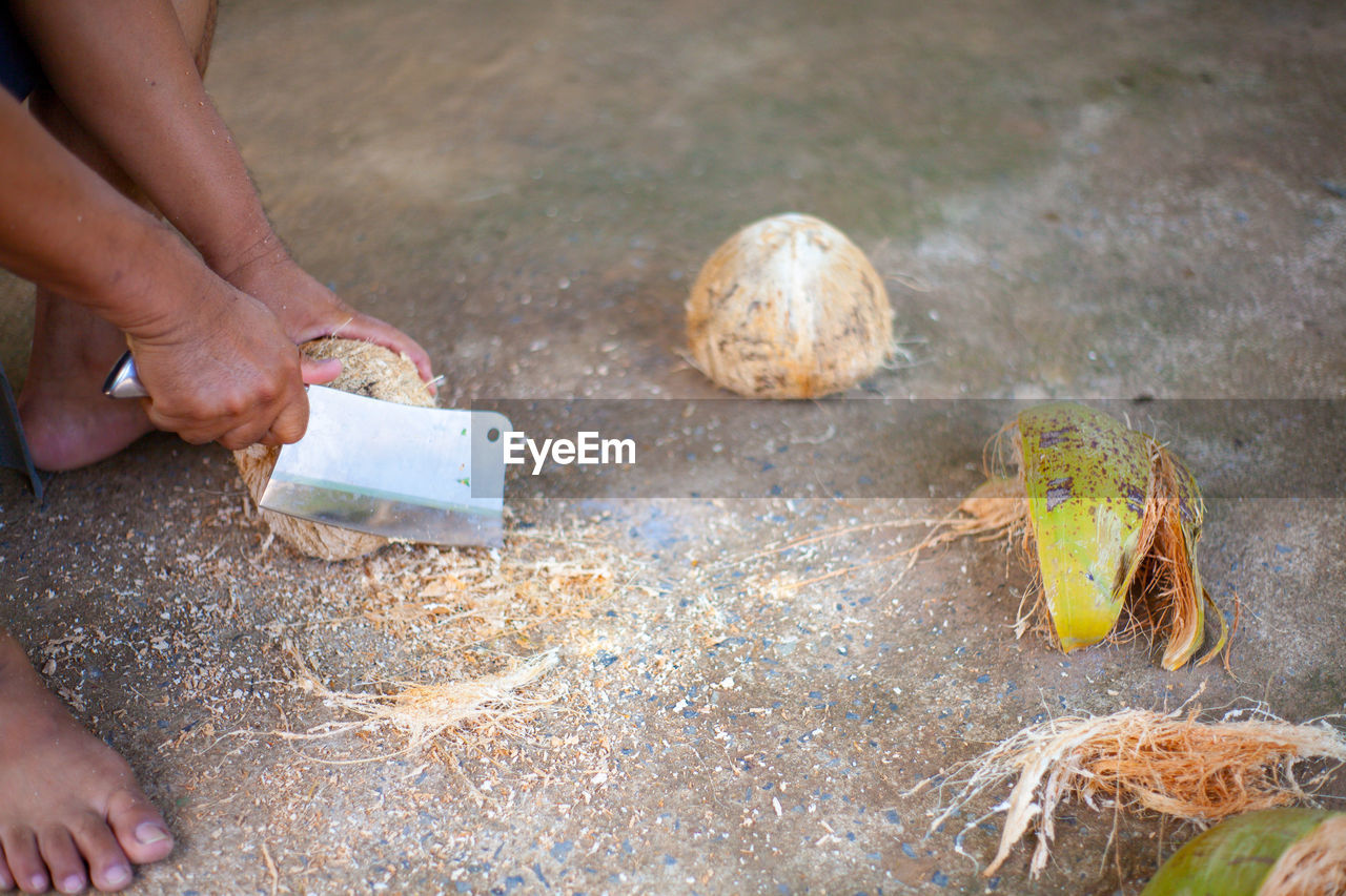 Low section of person cutting coconuts