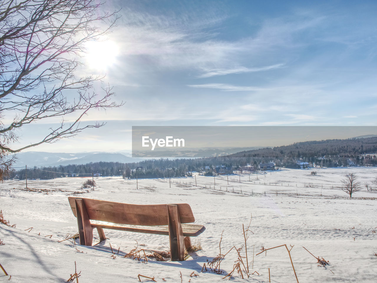Winter landscape, sunny day. footprints in the fresh snow lead to a wooden bench