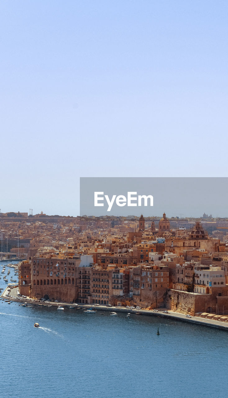 Aerial view of townscape by sea against clear sky