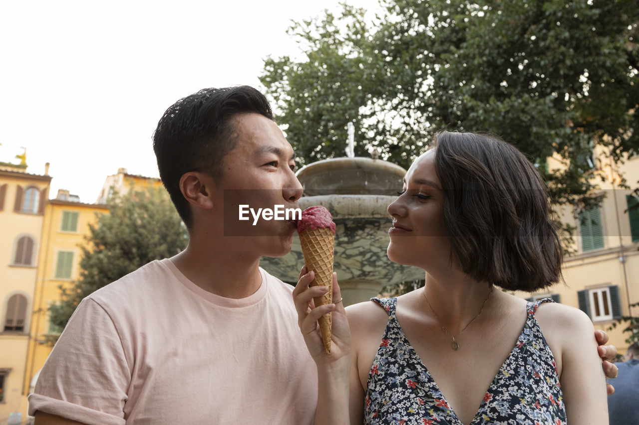 Attractive mixed race couple enjoying gelato in front of fountain