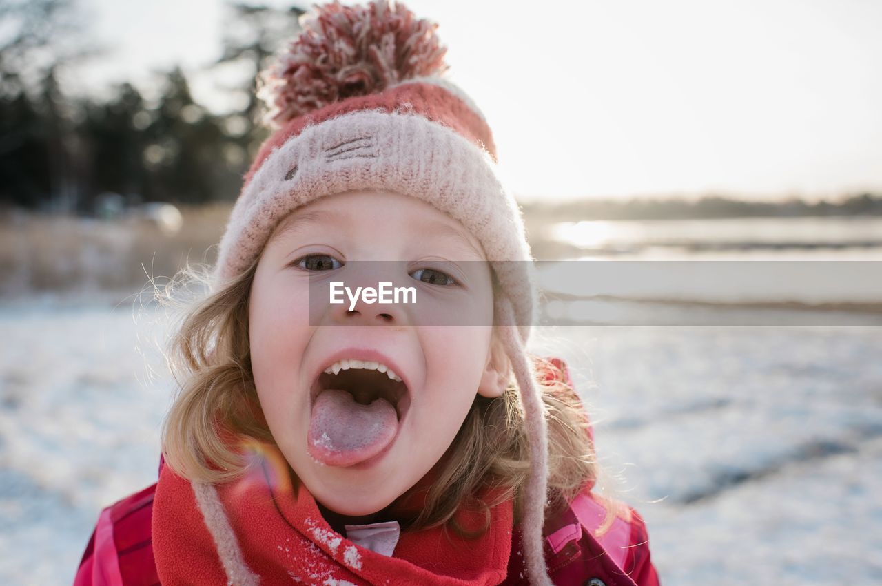 Young girl catching snow on her tongue outside in winter