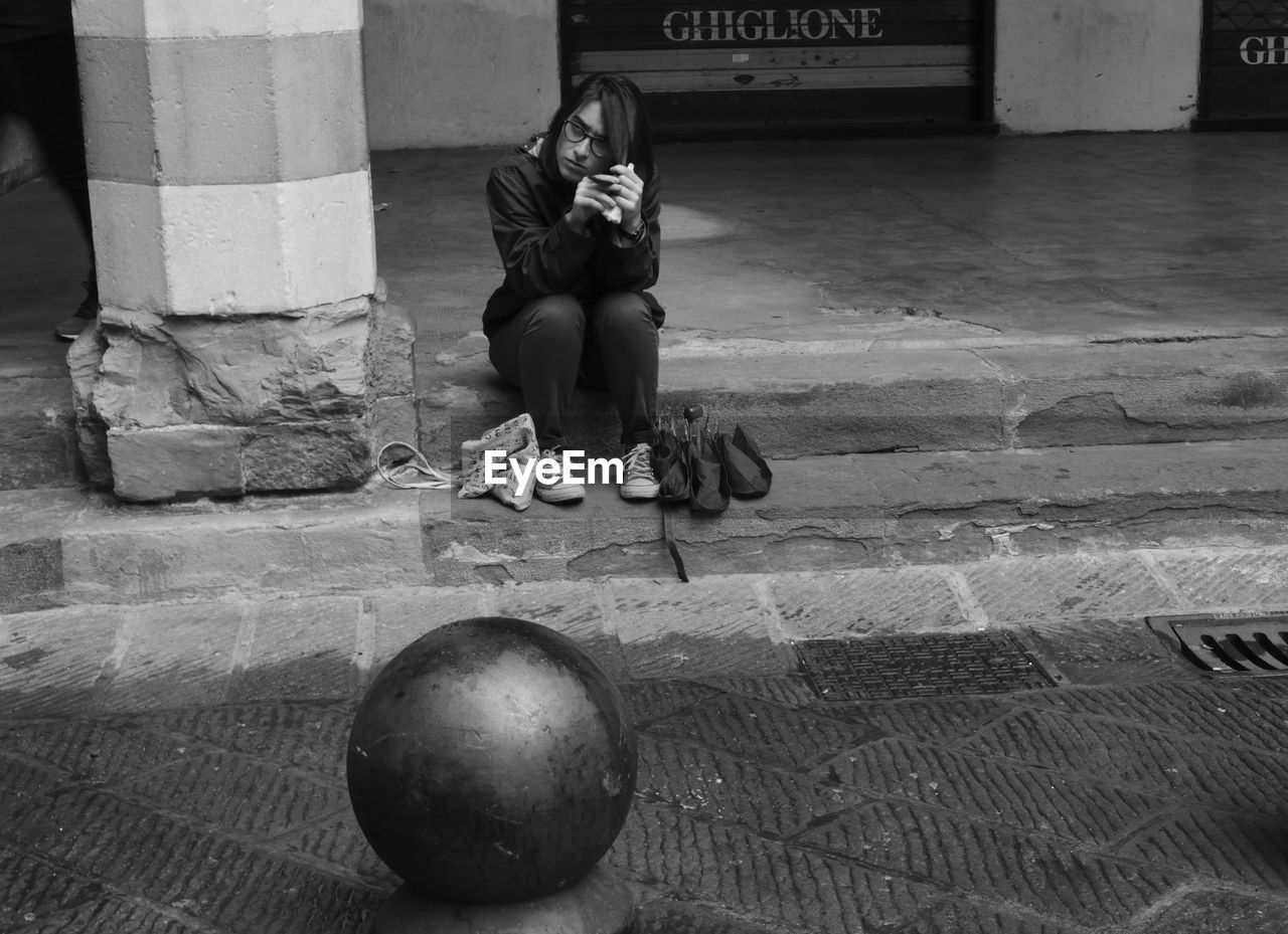 FULL LENGTH OF A WOMAN SITTING AT FLOOR