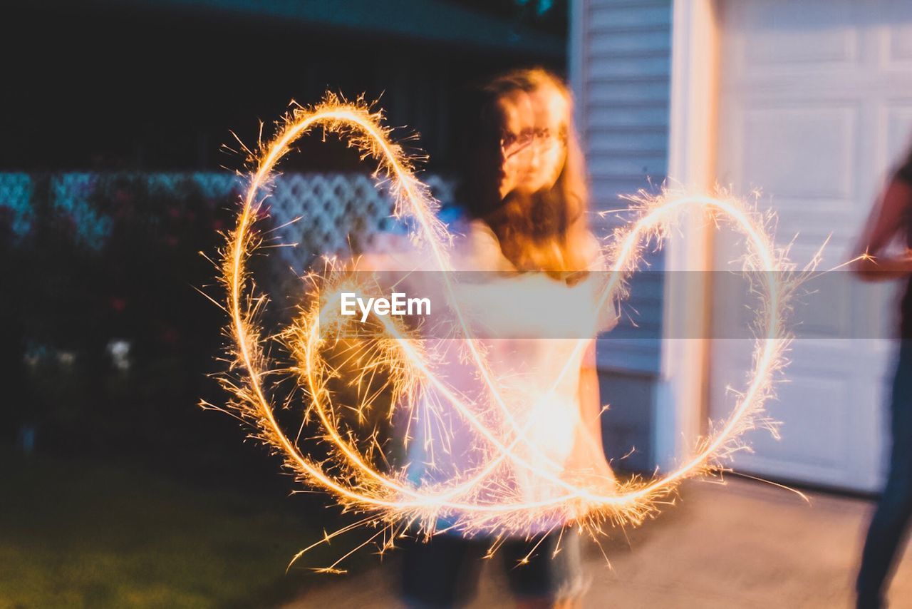 Blurred motion of girl with burning sparkler at night