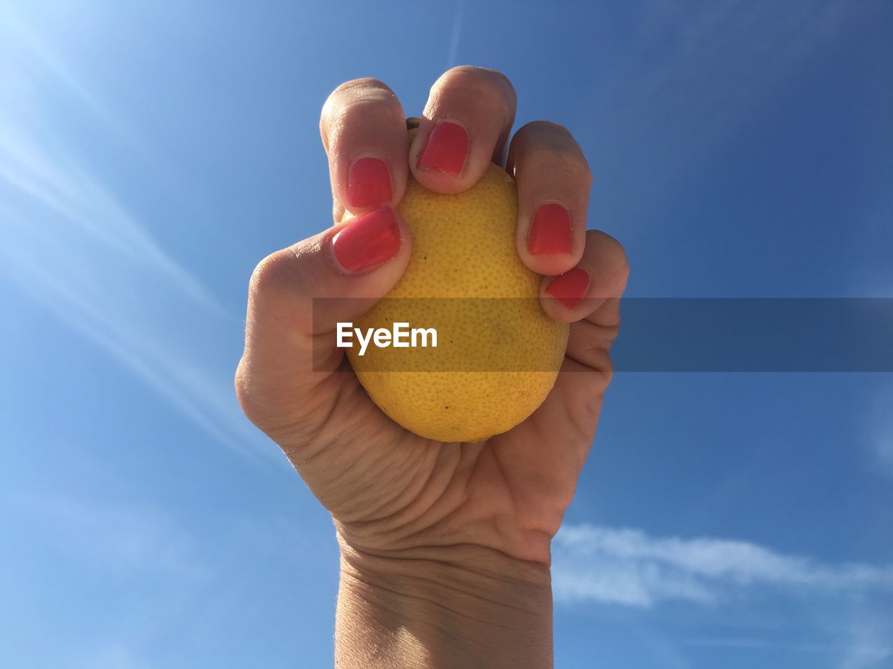 CLOSE-UP OF HAND HOLDING ICE CREAM AGAINST SKY