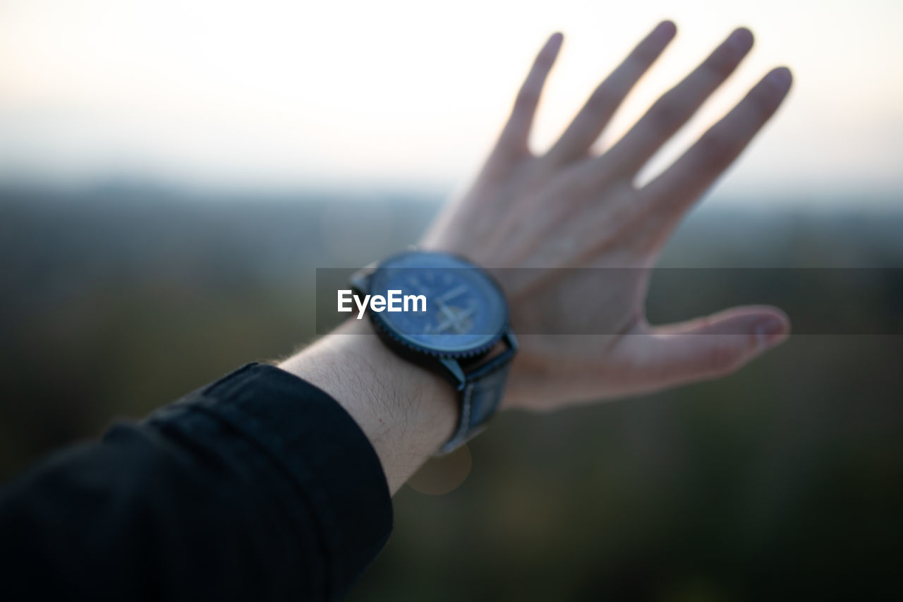 Cropped hand of man wearing watch gesturing outdoors